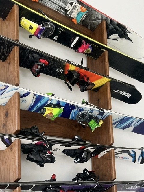 Walnut-stained 2Skip ski rack loaded with several pairs of skis